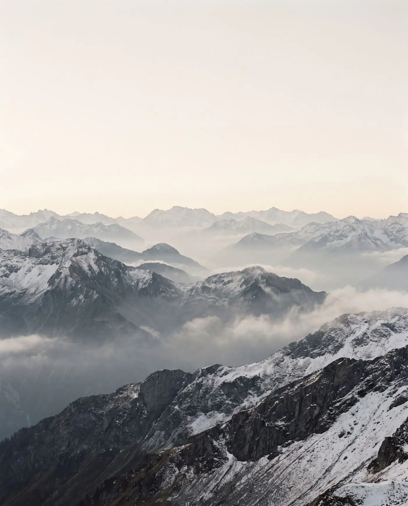 Snow-covered alpine ridgelines in soft morning haze